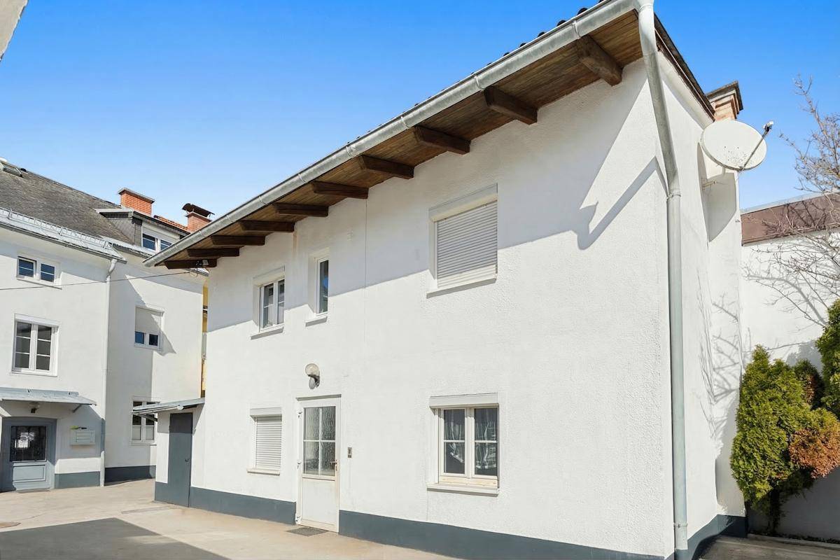 Rückansicht des Wohnhauses mit Holzdachüberstand und Satellitenschüssel an der Fassade.