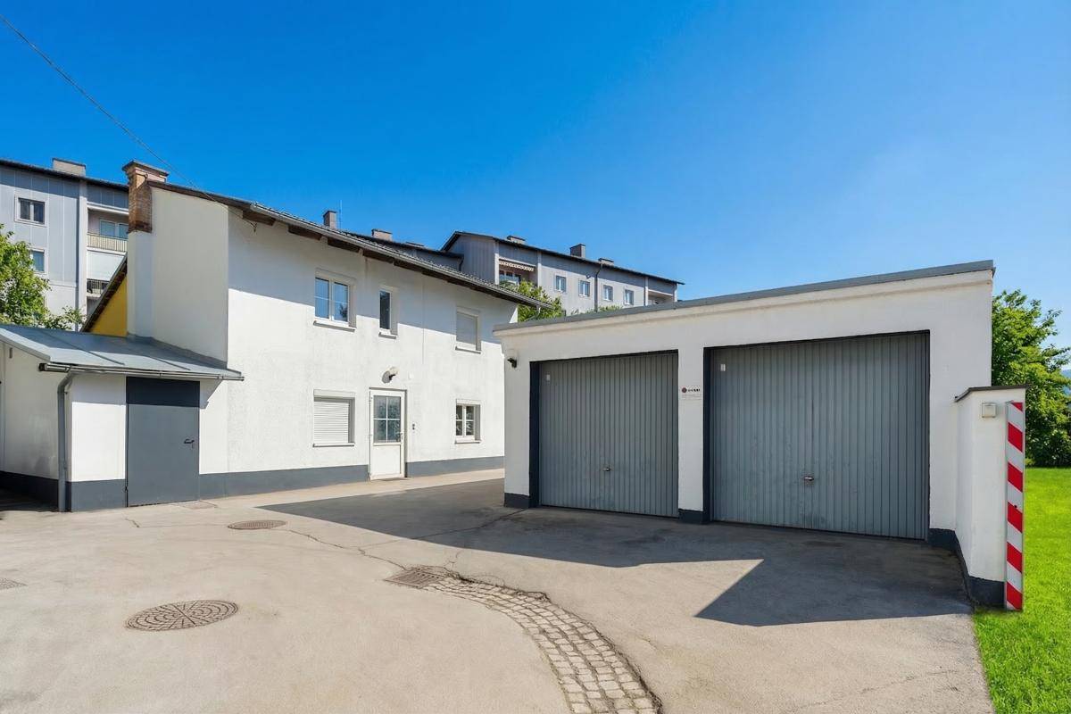 Rückseite des Wohnhauses mit zwei Garagen und gepflastertem Hofbereich.