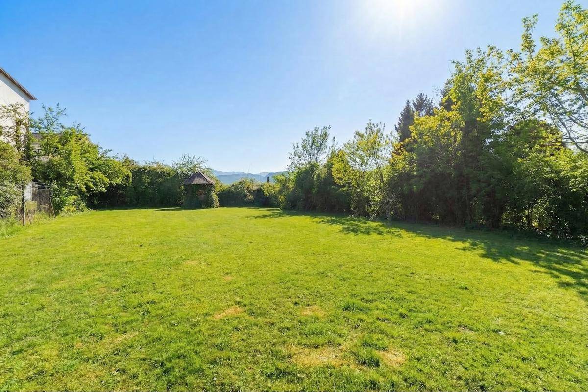 Weitläufiger Rasengarten mit Blick auf die umliegende Landschaft und Berge im Hintergrund.