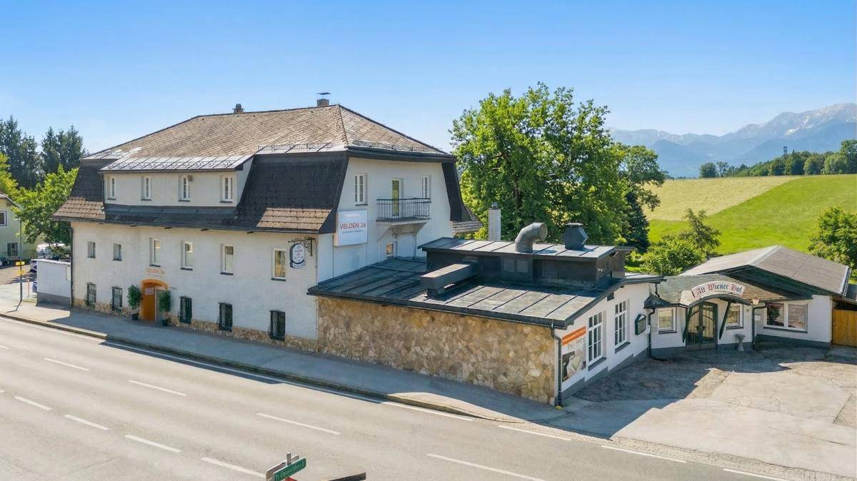 Ansicht des Gebäudes von der Straße mit einem angrenzenden Restaurant und Bergblick in der Ferne.