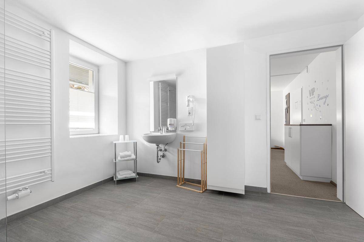 Helles Badezimmer mit Waschbecken, Handtuchheizkörper und Fenster.