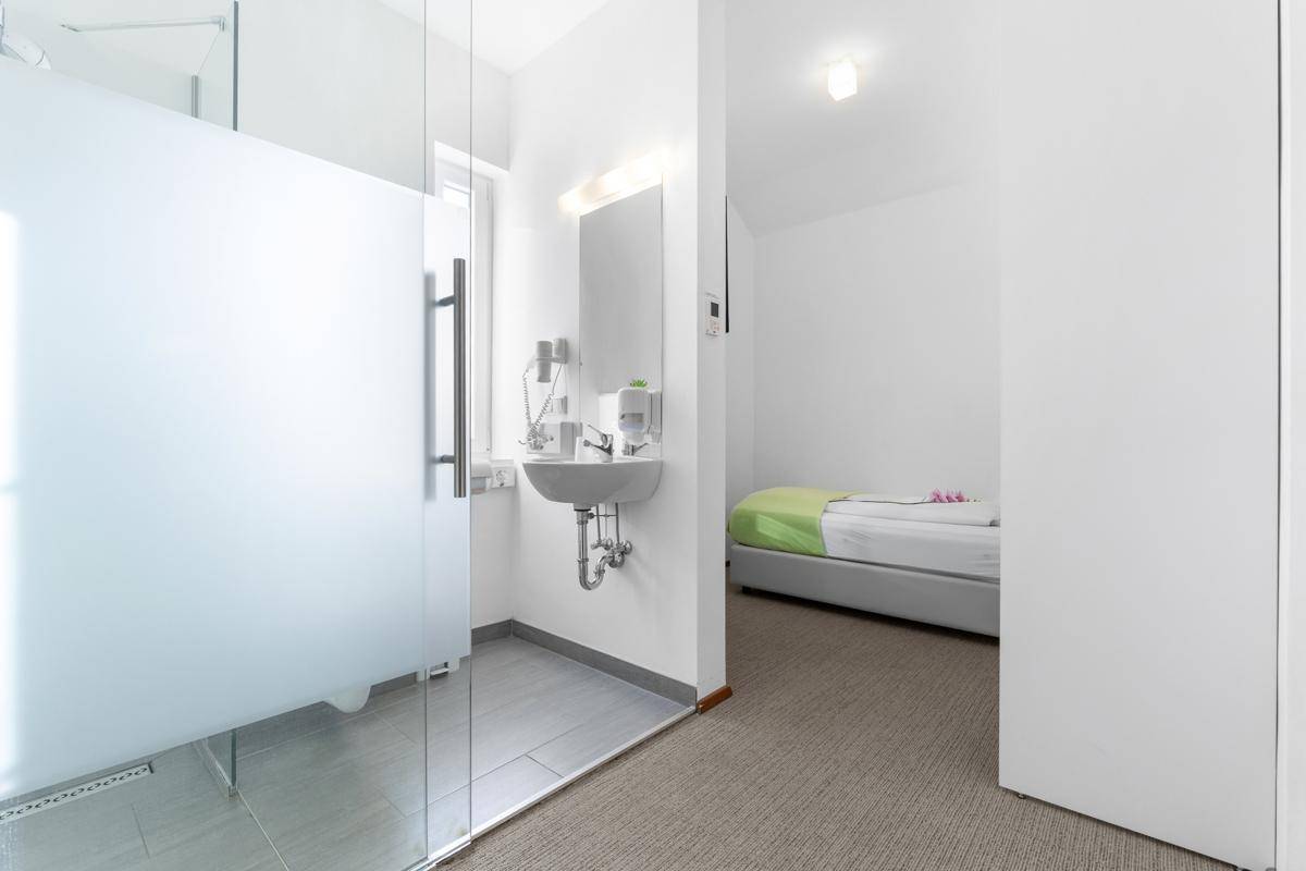 Schlafzimmer mit Teppichboden und offenem Badezimmerbereich mit Duschkabine.