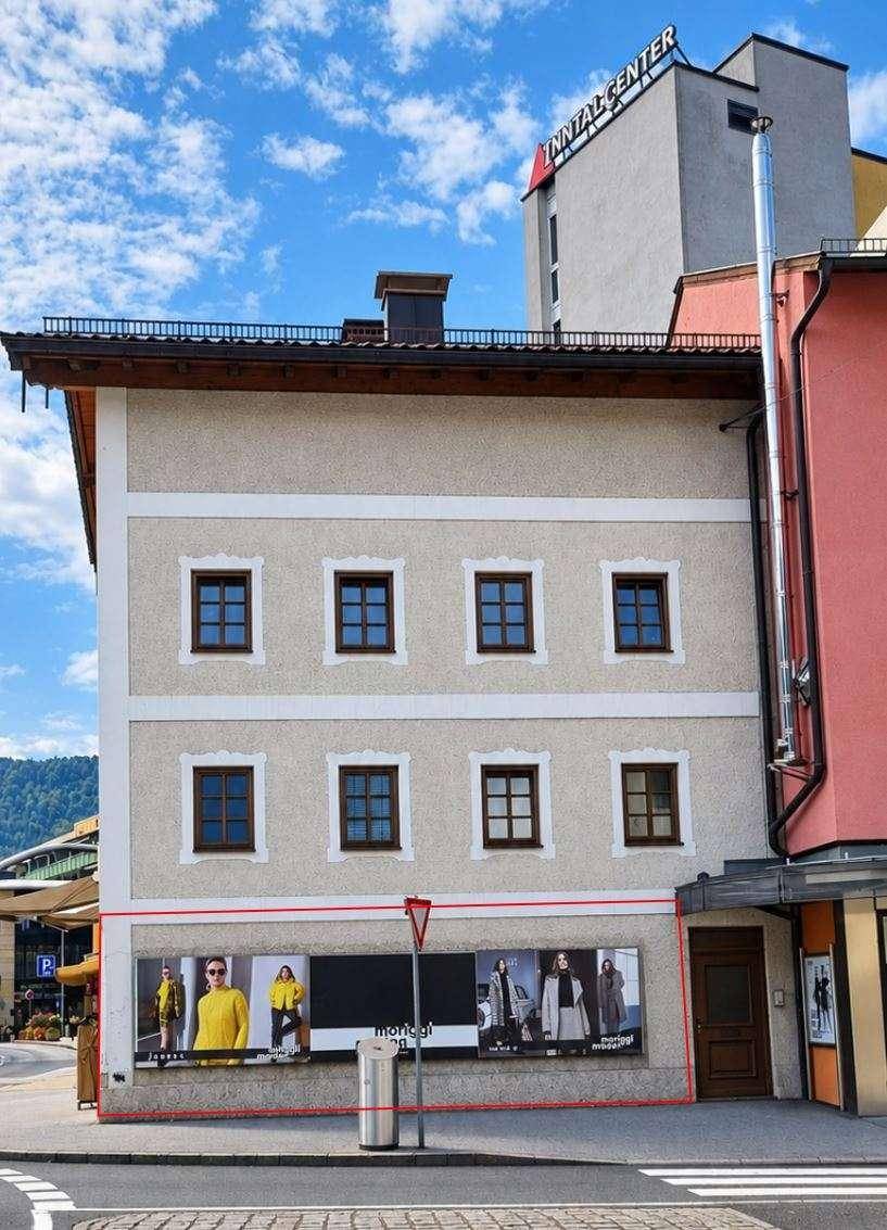 Seitenansicht des Gebäudes mit Plakaten im Erdgeschoss und angrenzendem modernen Bau.