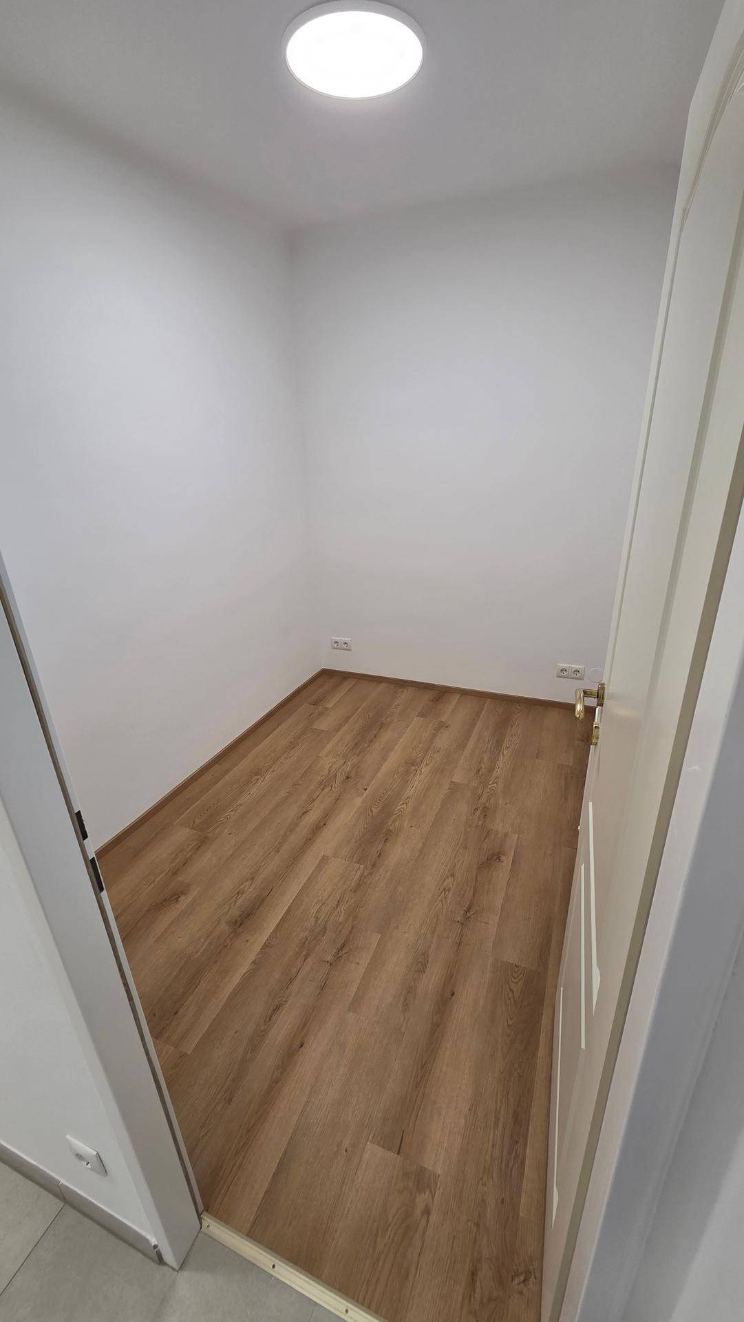 Kleines, helles Zimmer mit Laminatboden und weiß gestrichenen Wänden, ideal als Kinderzimmer.