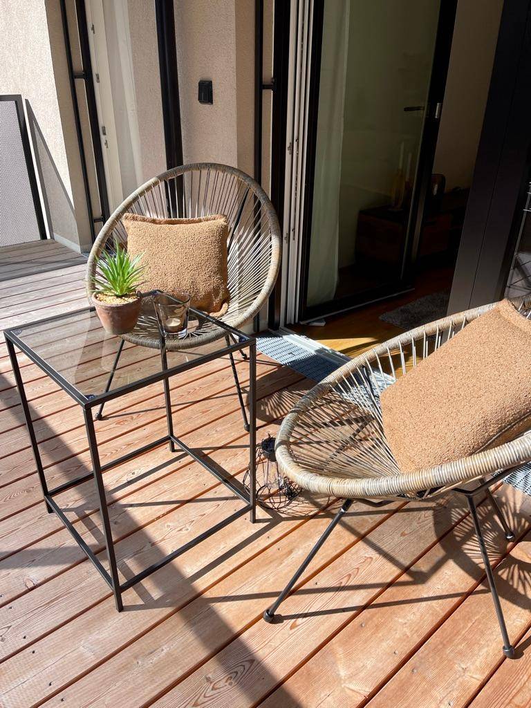 Sonniger Balkon mit Holzfußboden und modernen Outdoor-Sitzmöbeln für entspannte Stunden.