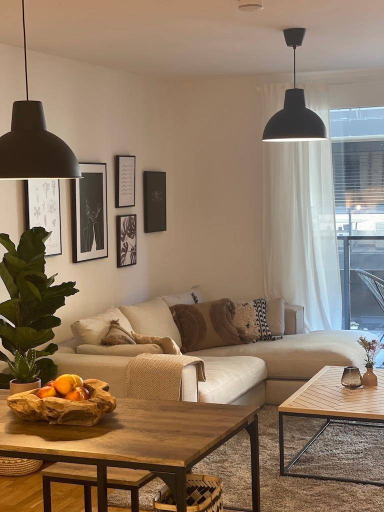 Gemütliches Wohnzimmer mit Ecksofa, Zugang zum Balkon und viel natürlichem Licht.