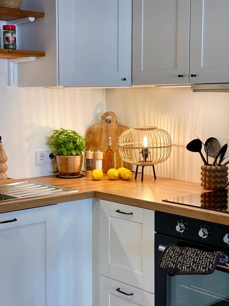 Küchenarbeitsplatte mit Induktionskochfeld, Backofen und dekorativer Lampe in modernem Design.