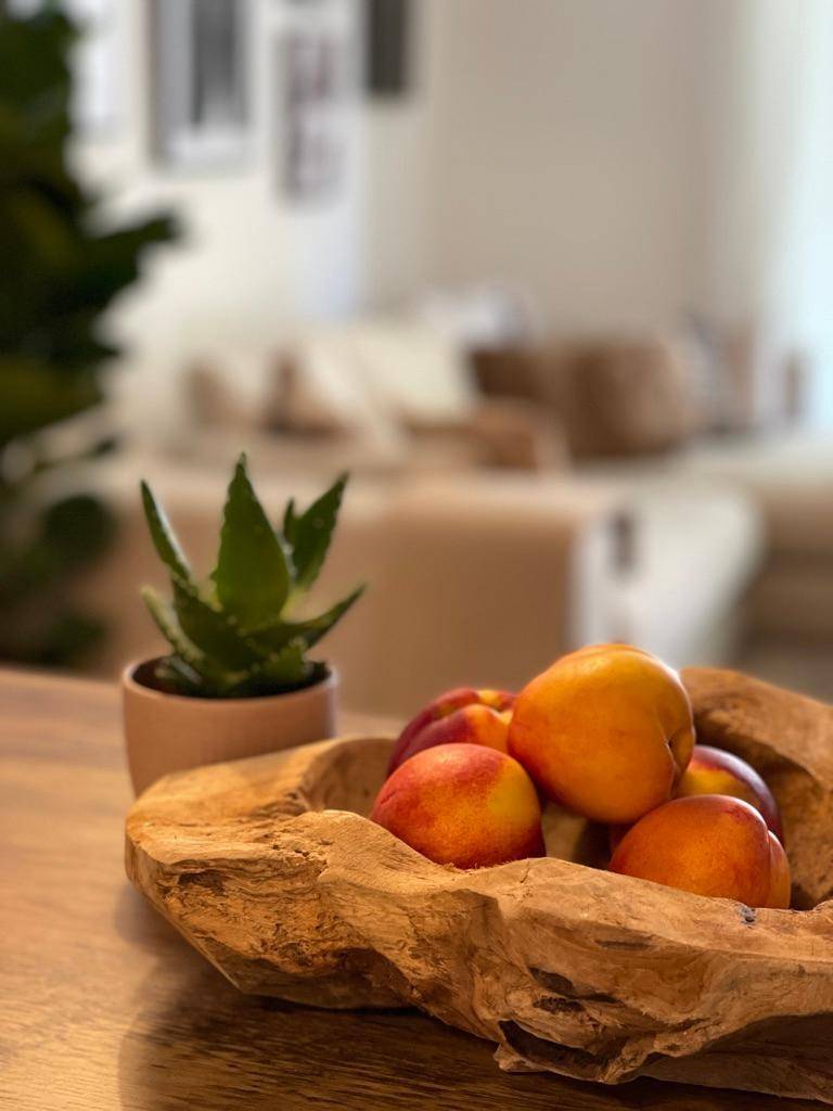 Detailaufnahme einer Holzschale mit frischen Früchten auf einem rustikalen Holztisch.