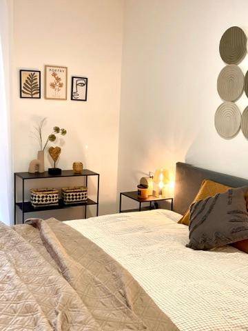 Helles Schlafzimmer mit Doppelbett, Nachttischen und stilvoller Wanddekoration in neutralen Tönen.