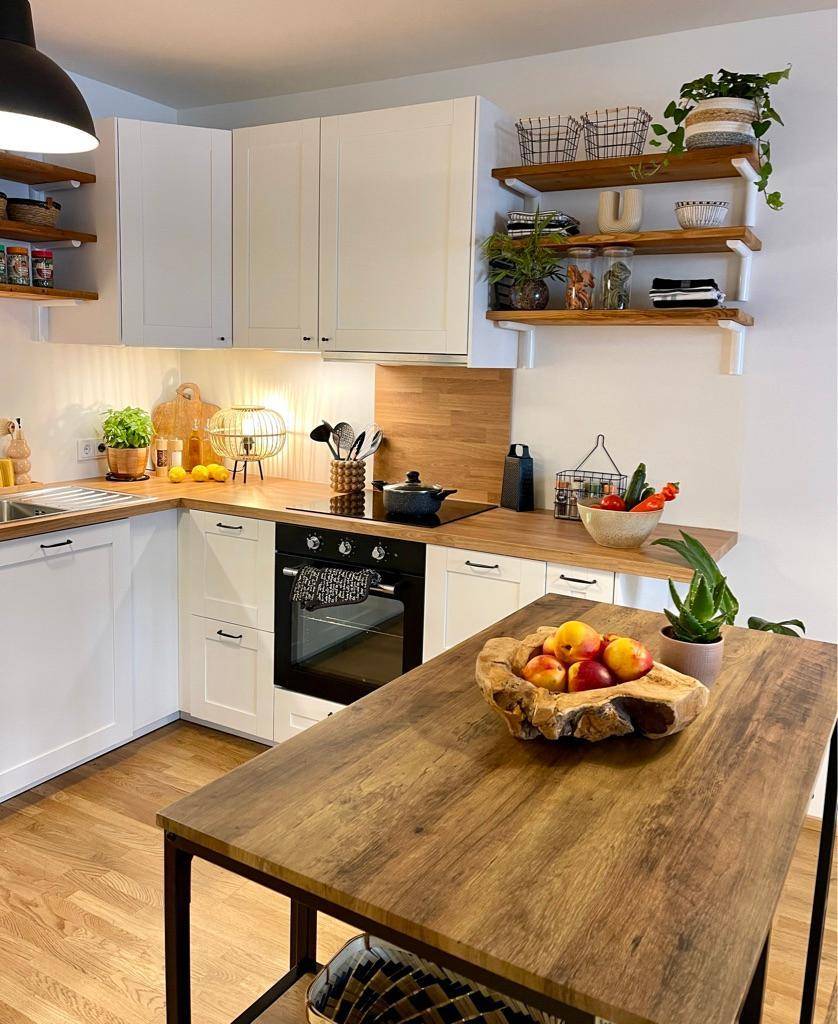 Moderne Einbauküche mit weißen Schränken, Holz-Arbeitsplatten und offenen Regalen.