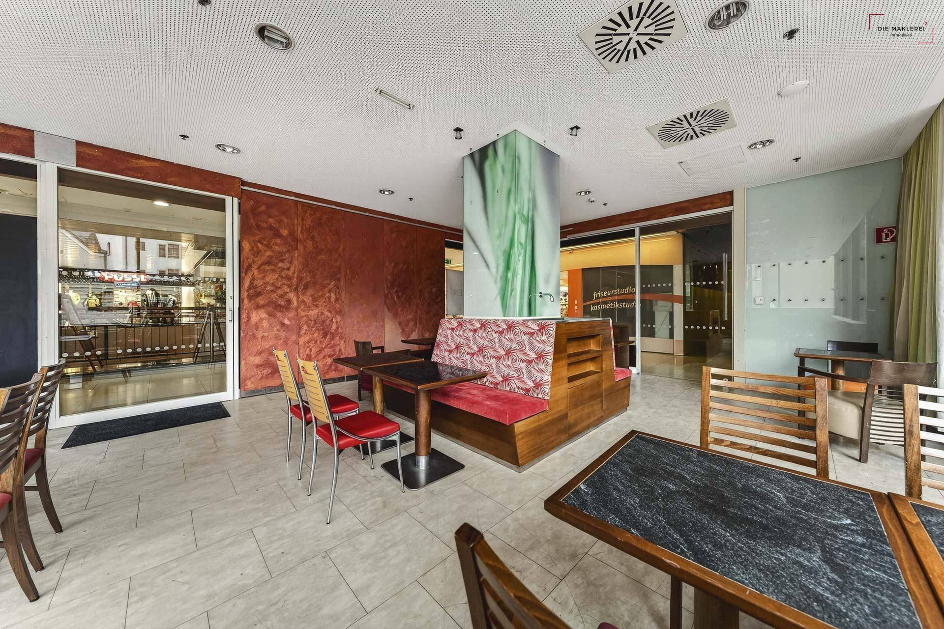 Offener Gastronomiebereich mit verschiedenen Sitzgelegenheiten und einem zentralen, dekorierten Pfeiler.