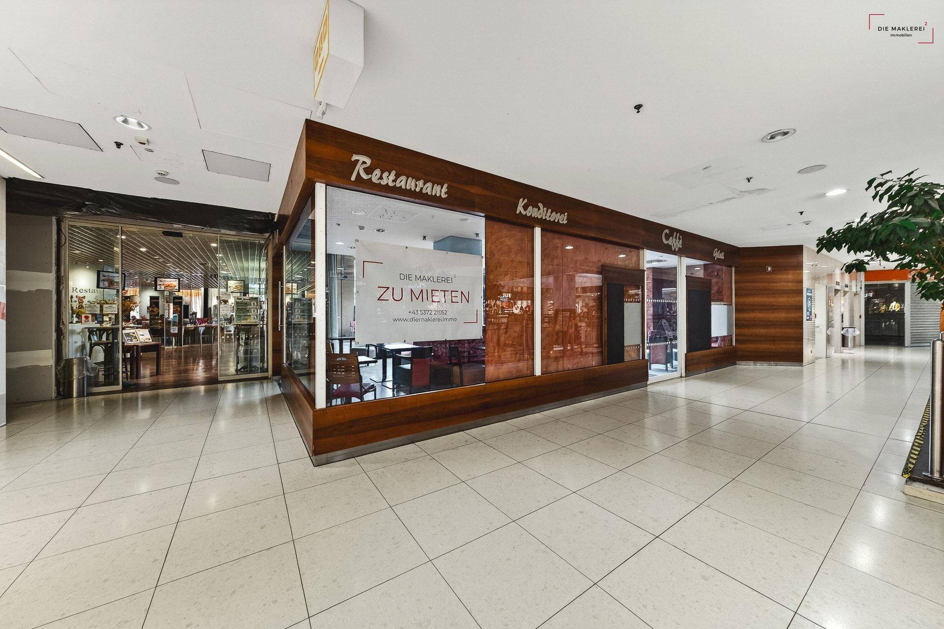 Langer Flur in einem Einkaufszentrum mit einem Geschäft, das als Restaurant, Konditorei und Café dient.