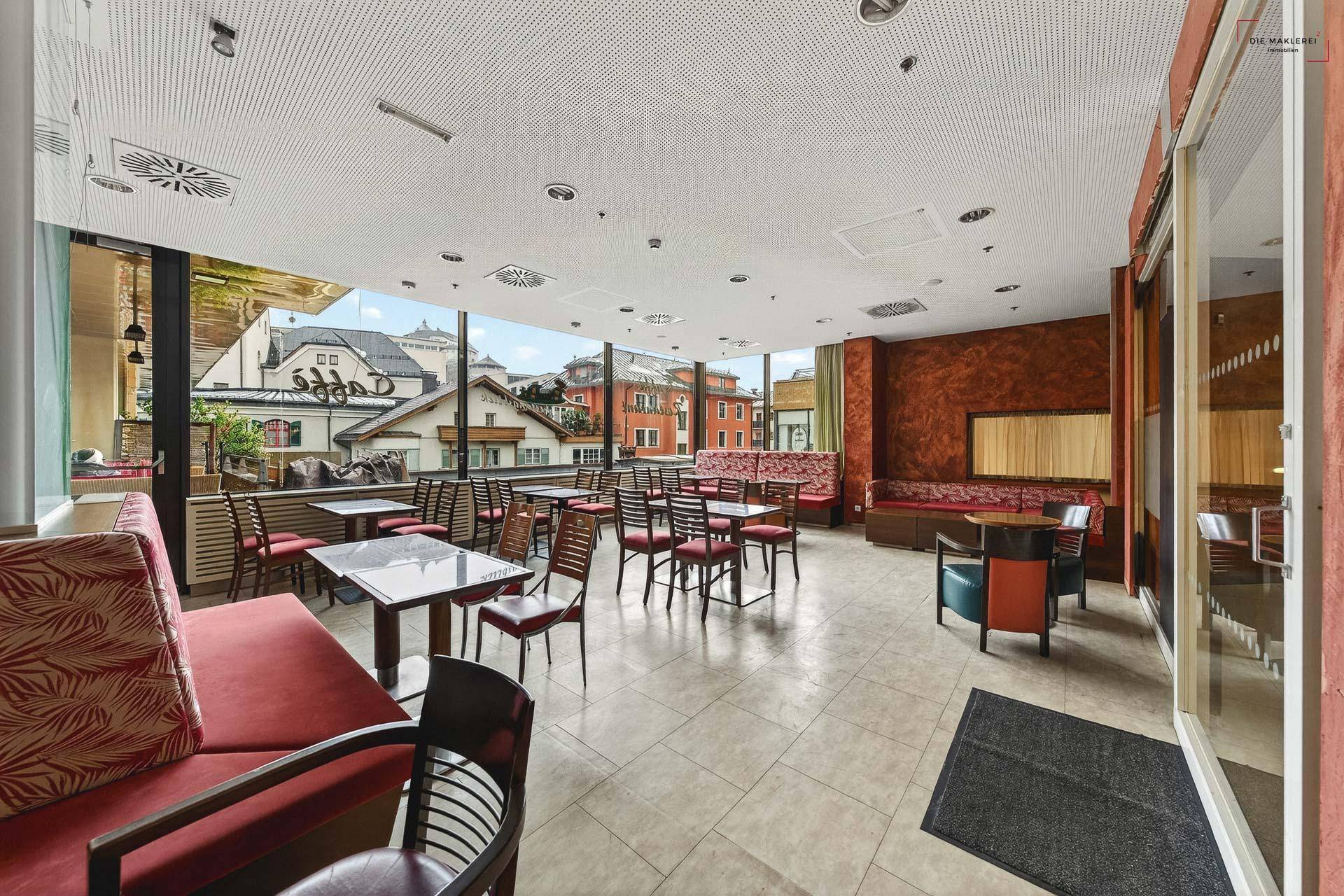 Weitläufiger Gastronomiebereich mit verschiedenen Sitzgelegenheiten und großen Fenstern mit Stadtblick.