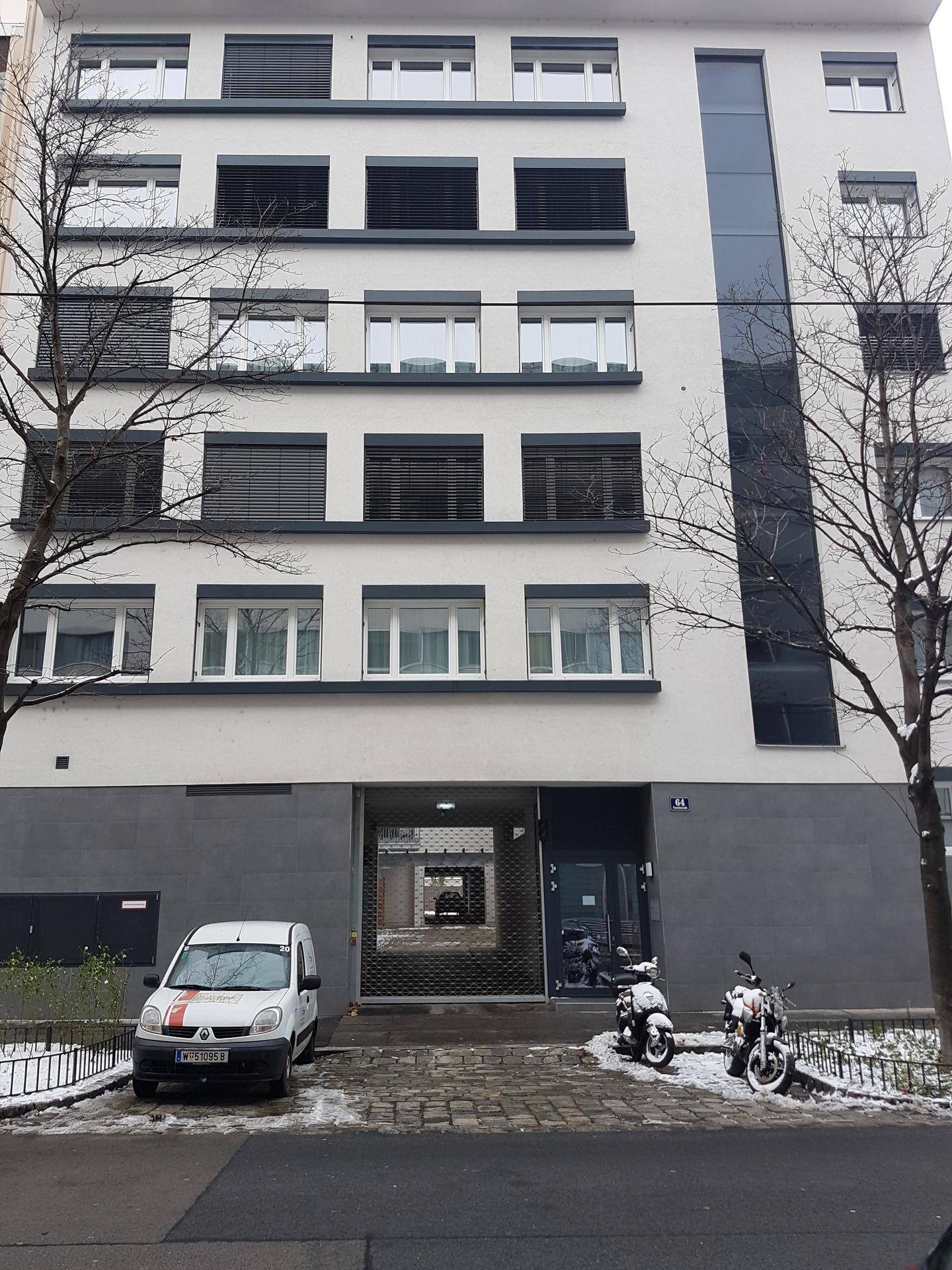 Moderne Gebäudefassade mit vielen Fenstern und Rollläden an einem verschneiten Wintertag.