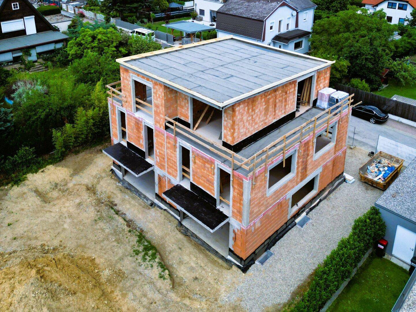 Luftaufnahme eines im Bau befindlichen Neubaus mit massiver Ziegelkonstruktion und Flachdach.