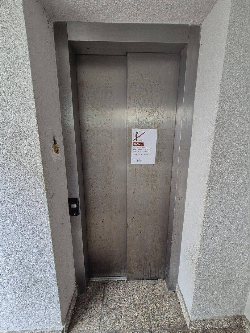 Metallene Aufzugstür in einem Flur, die den Zugang zu den oberen Etagen ermöglicht.