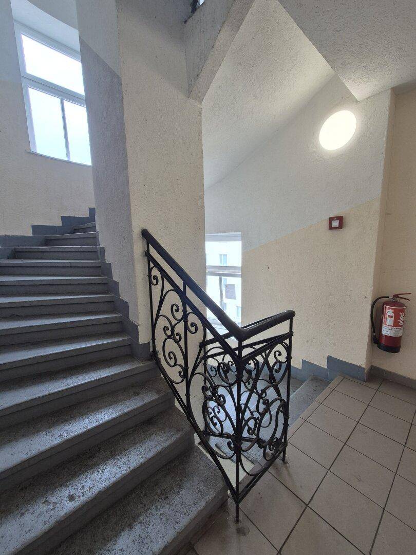 Treppenhaus mit schmiedeeisernem Geländer und einem Fenster, das für natürliches Licht sorgt.