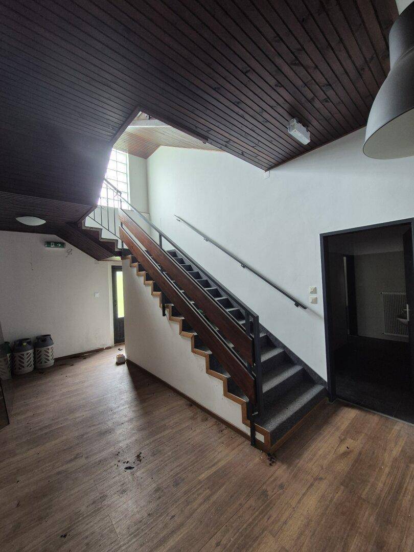 Treppenhaus mit Holzverkleidung an der Decke und Geländer, führt in obere Etagen.