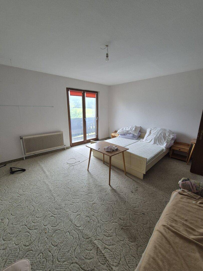 Schlafzimmer mit zwei Einzelbetten, kleinem Tisch und Zugang zu einem Balkon.