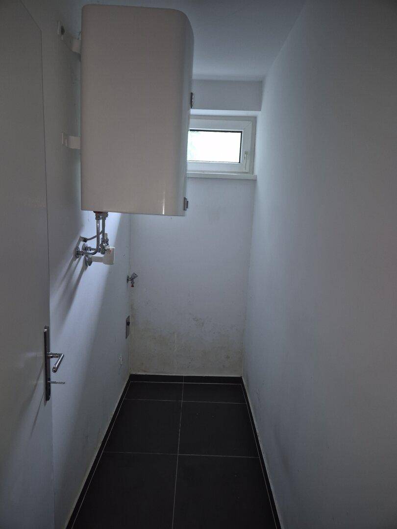 Kleiner Abstellraum mit Warmwasserboiler und Fenster, ideal für zusätzlichen Stauraum.