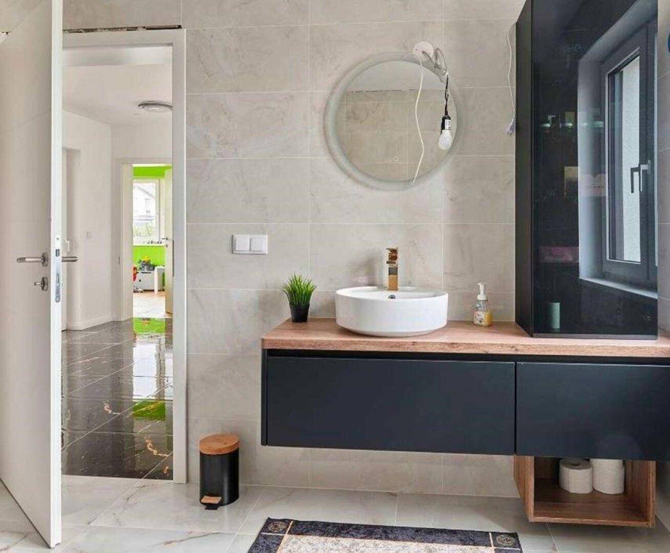 Modernes Badezimmer mit schwebendem Waschtisch, rundem Spiegel und hellem Ambiente.