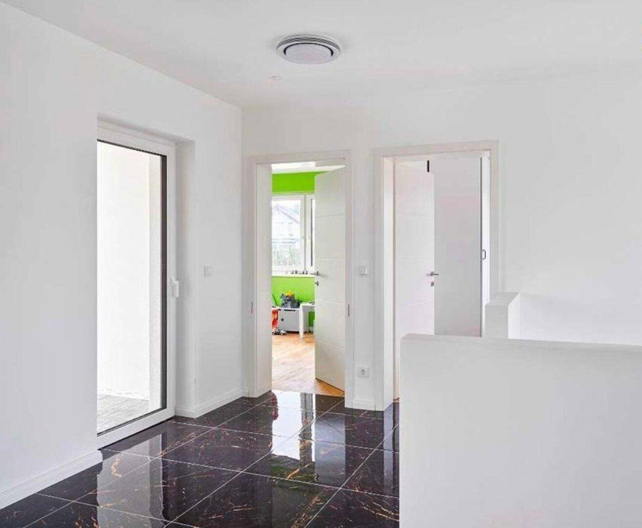 Heller Flur im Obergeschoss mit glänzenden Fliesen und Zugang zu weiteren Räumen.