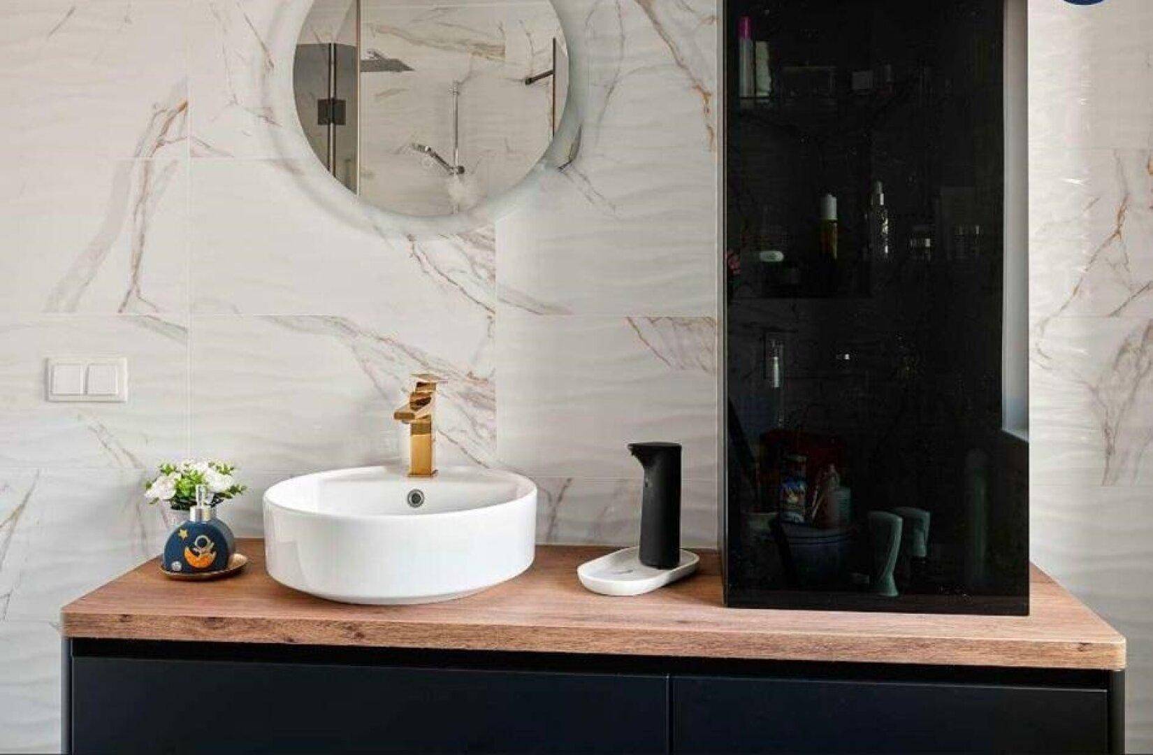 Modernes Badezimmer mit Aufsatzwaschbecken, Holzplatte und eleganten Marmorfliesen.