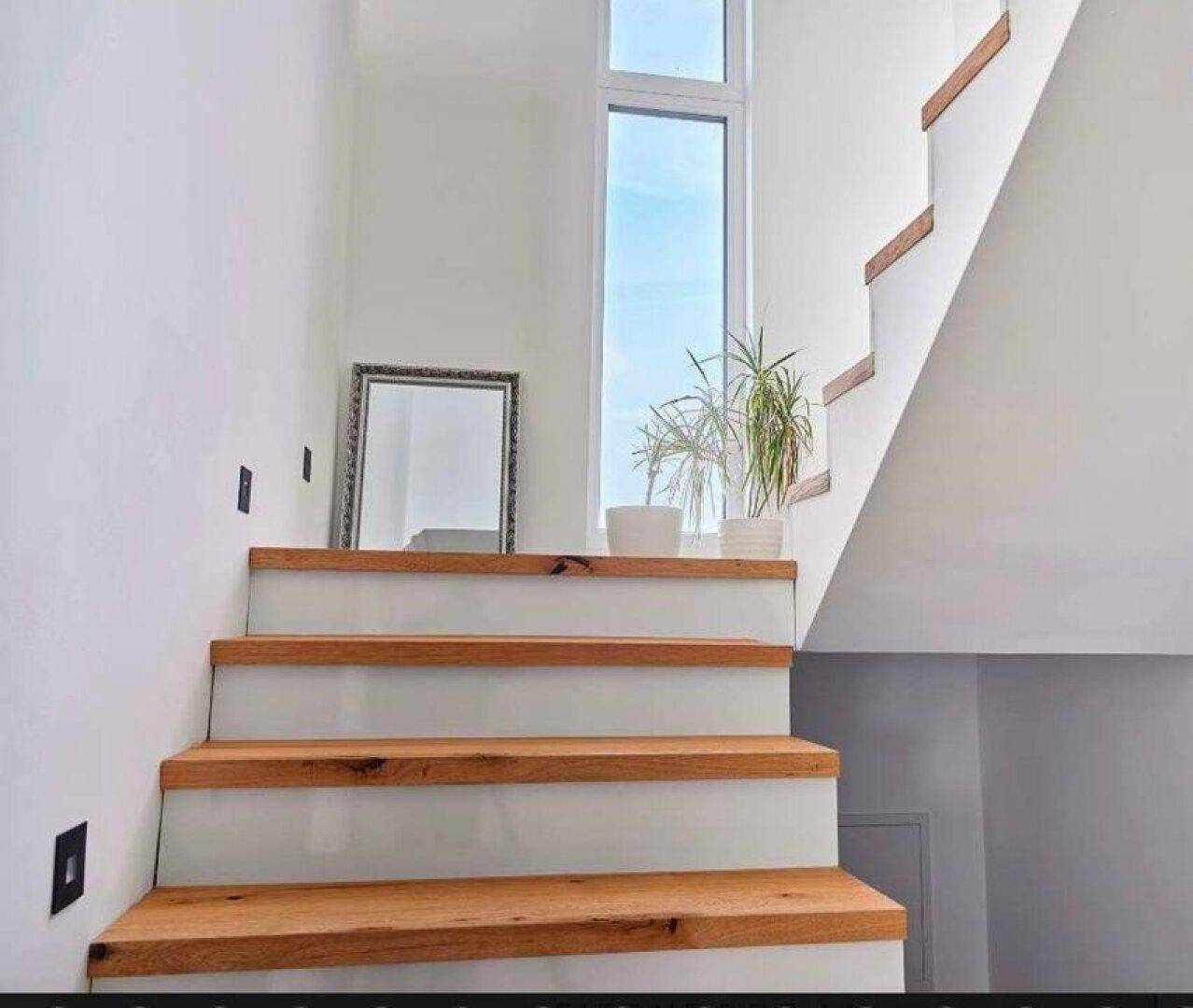 Helle Holztreppe mit großem Fenster, das viel Tageslicht hereinlässt.