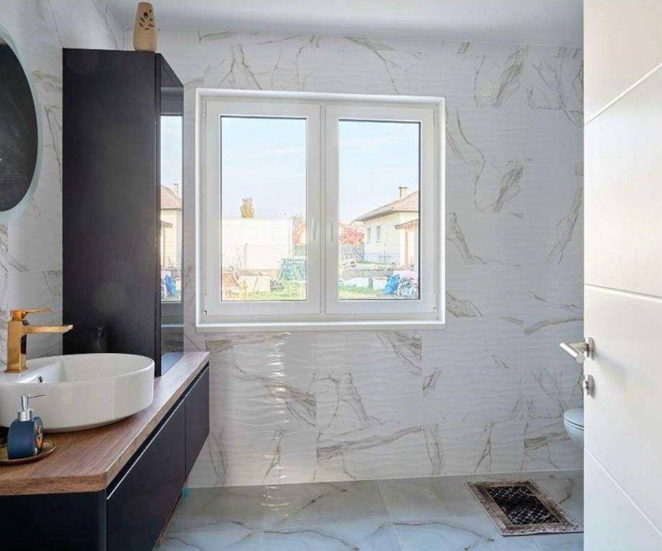 Helles Badezimmer mit Fenster, modernen Fliesen und wandhängendem WC.