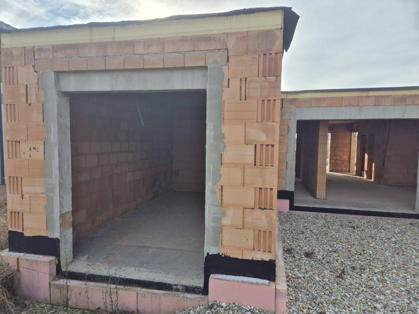 Detailansicht des Rohbaus mit einer großen Öffnung, möglicherweise für eine Garage.