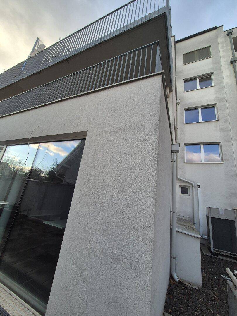 Moderne Gebäudefassade mit großen Fensterfronten und mehreren Balkonen, die eine zeitgemäße Architektur aufweisen.