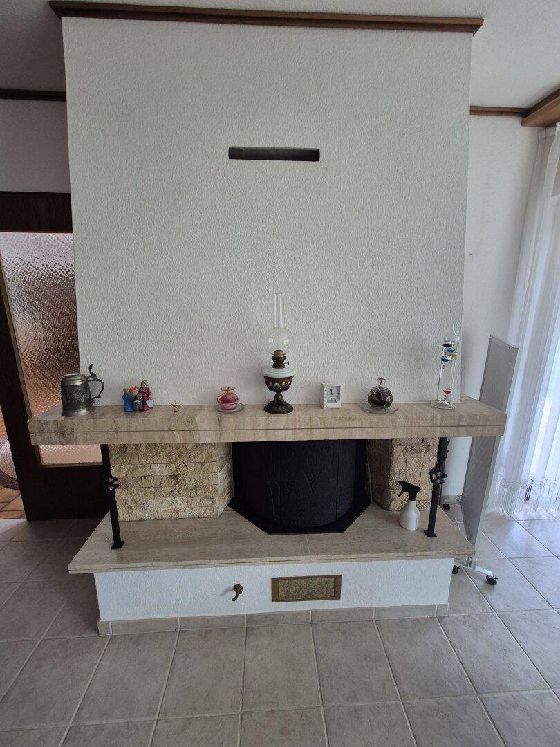 Detailansicht eines traditionellen Kamins mit Steinelementen und Ablagefläche im Wohnzimmer.