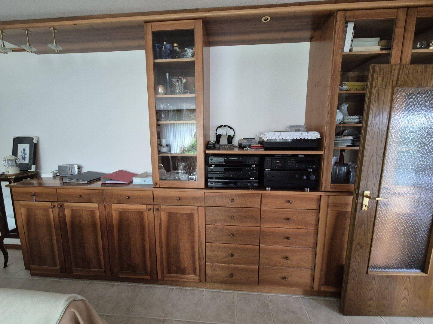 Große, maßgefertigte Holzschrankwand mit Vitrinen und integriertem Mediencenter im Wohnzimmer.