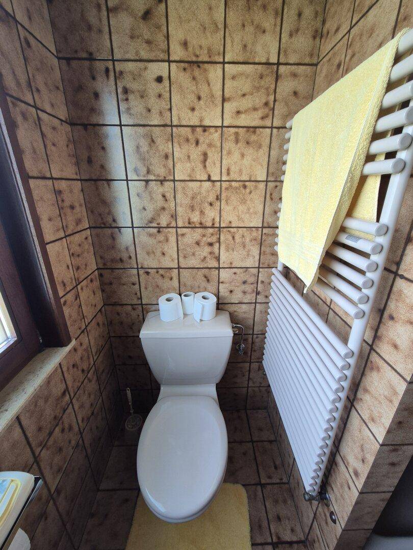 Separate Toilette mit Fenster und Handtuchheizkörper, vollständig gefliest.
