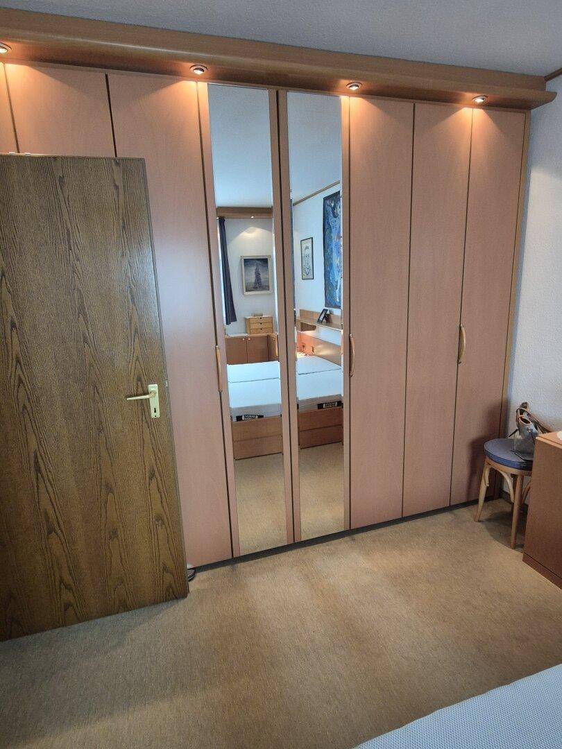 Schlafzimmer mit großem Spiegelschrank und Teppichboden, bietet viel Stauraum.