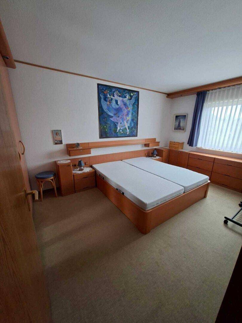 Schlafzimmer mit Doppelbett, Teppichboden und Holzmöbeln, bietet eine ruhige Atmosphäre.