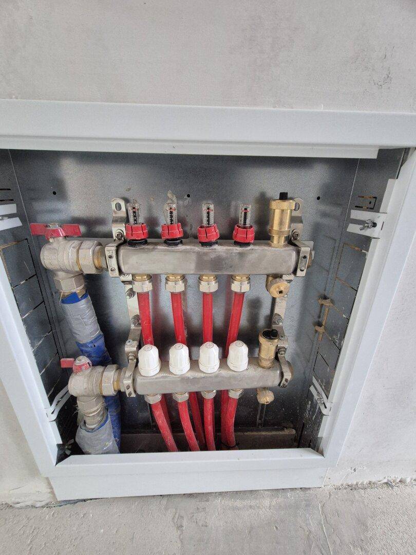Verteiler für die Fußbodenheizung in einem Neubau, sichtbar in einer Wandnische.