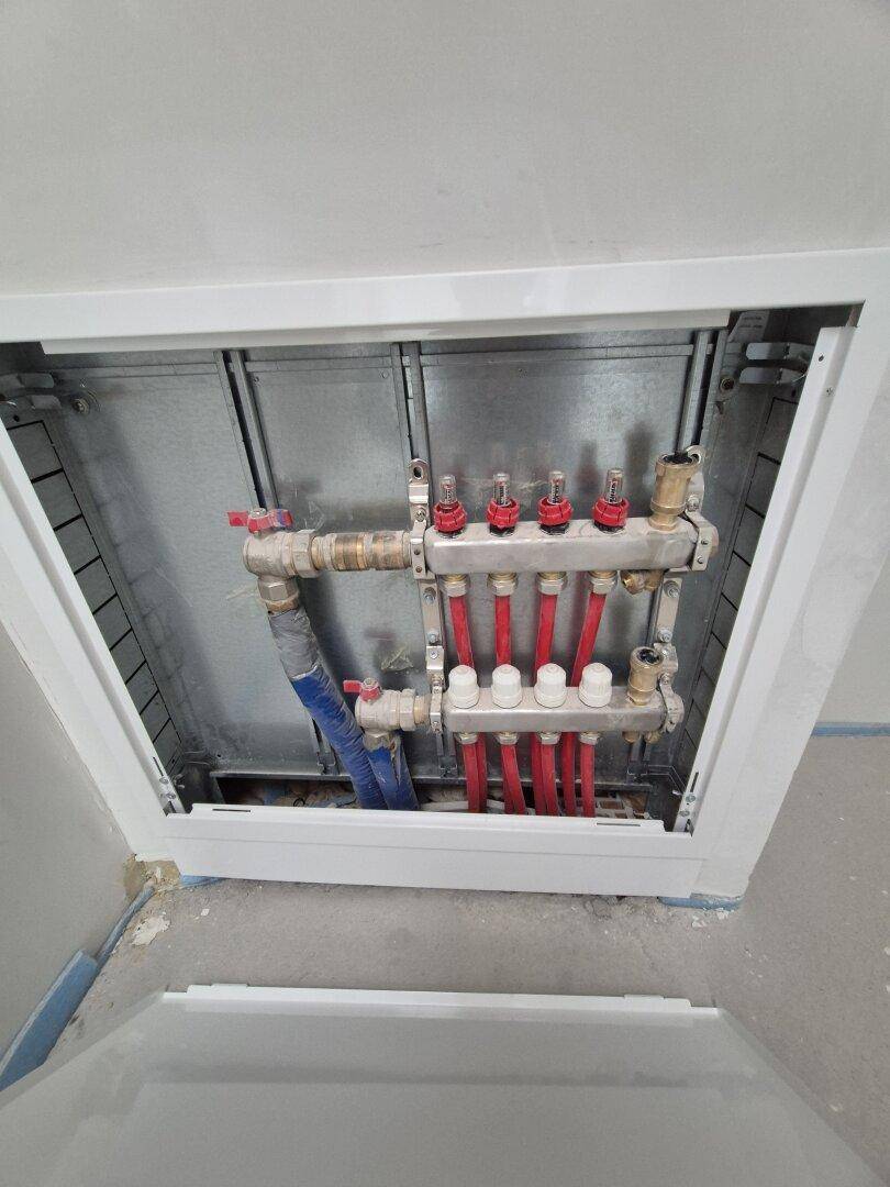 Verteiler für die Fußbodenheizung in einem Neubau, sichtbar in einer Wandnische.