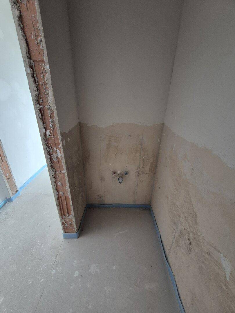 Unfertiger Raum mit sichtbaren Wasseranschlüssen, vorbereitet für ein Gäste-WC oder Bad.