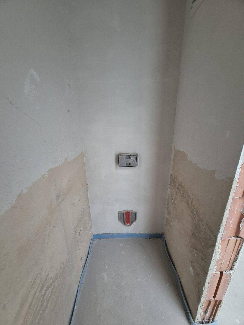 Unfertiger Raum mit sichtbaren Wasseranschlüssen, vorbereitet für ein Gäste-WC oder Bad.