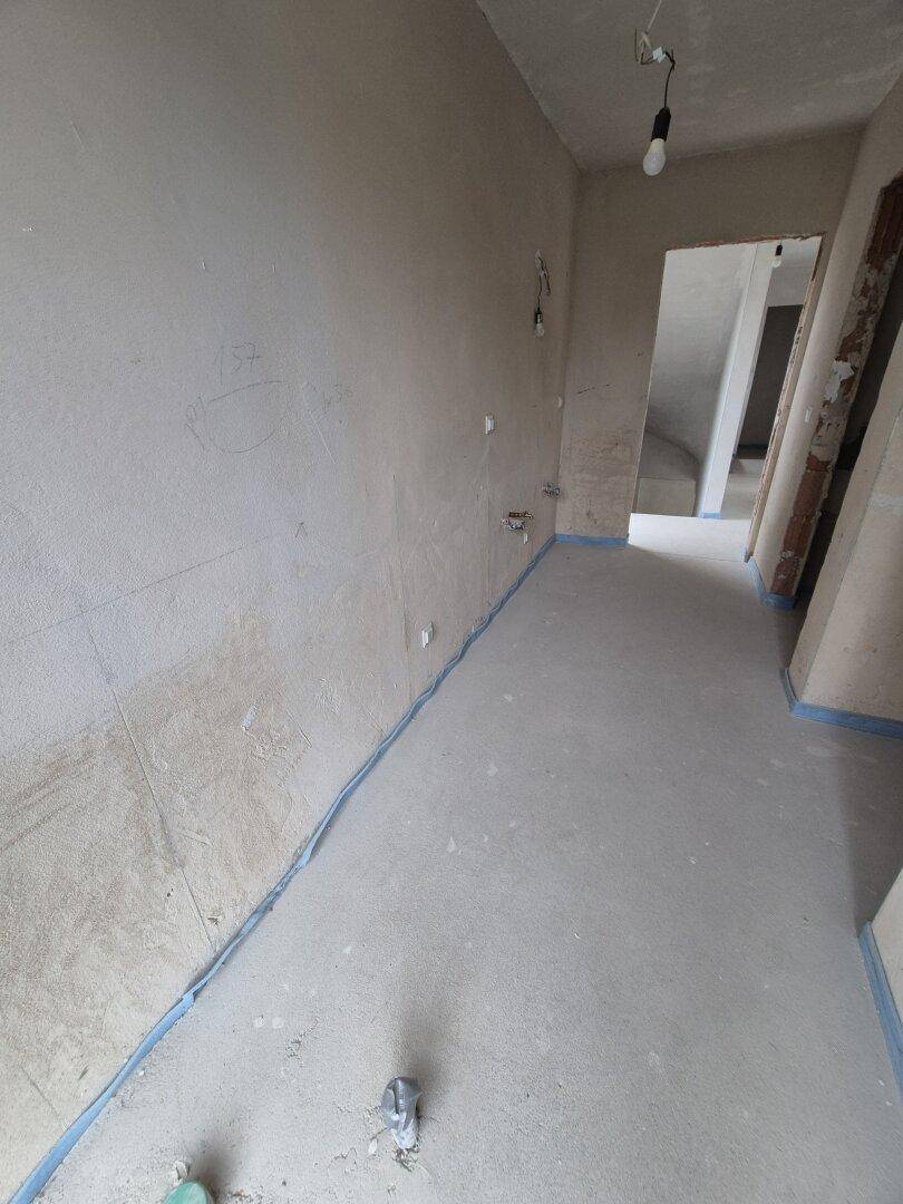 Unfertiger Innenraum mit Rohbauwänden und Betonboden, bereit für den weiteren Ausbau des Gebäudes.