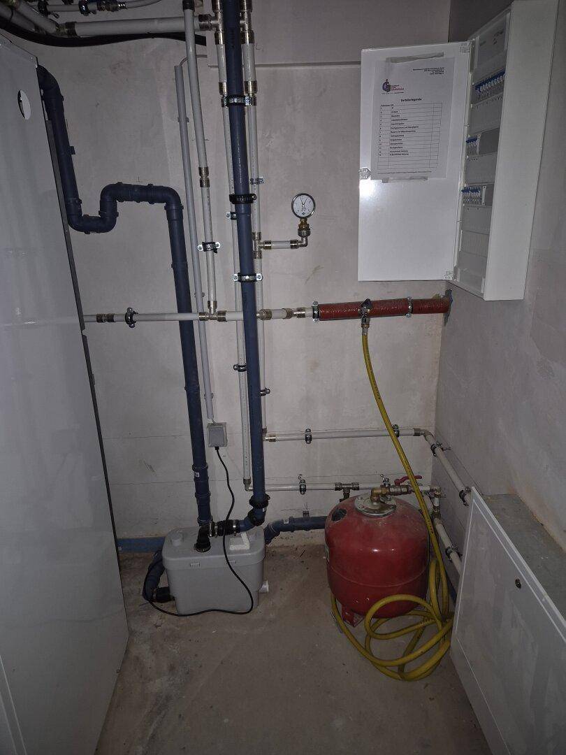 Technikraum mit umfangreichen Rohrleitungen, Warmwasserspeicher und Elektroverteilung im Neubau.