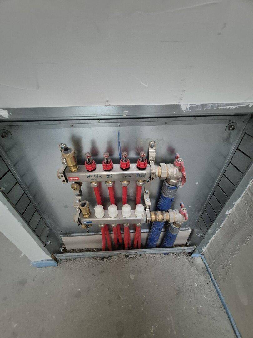 Verteiler für die Fußbodenheizung in einem Technikschacht, ordentlich installiert und zugänglich.