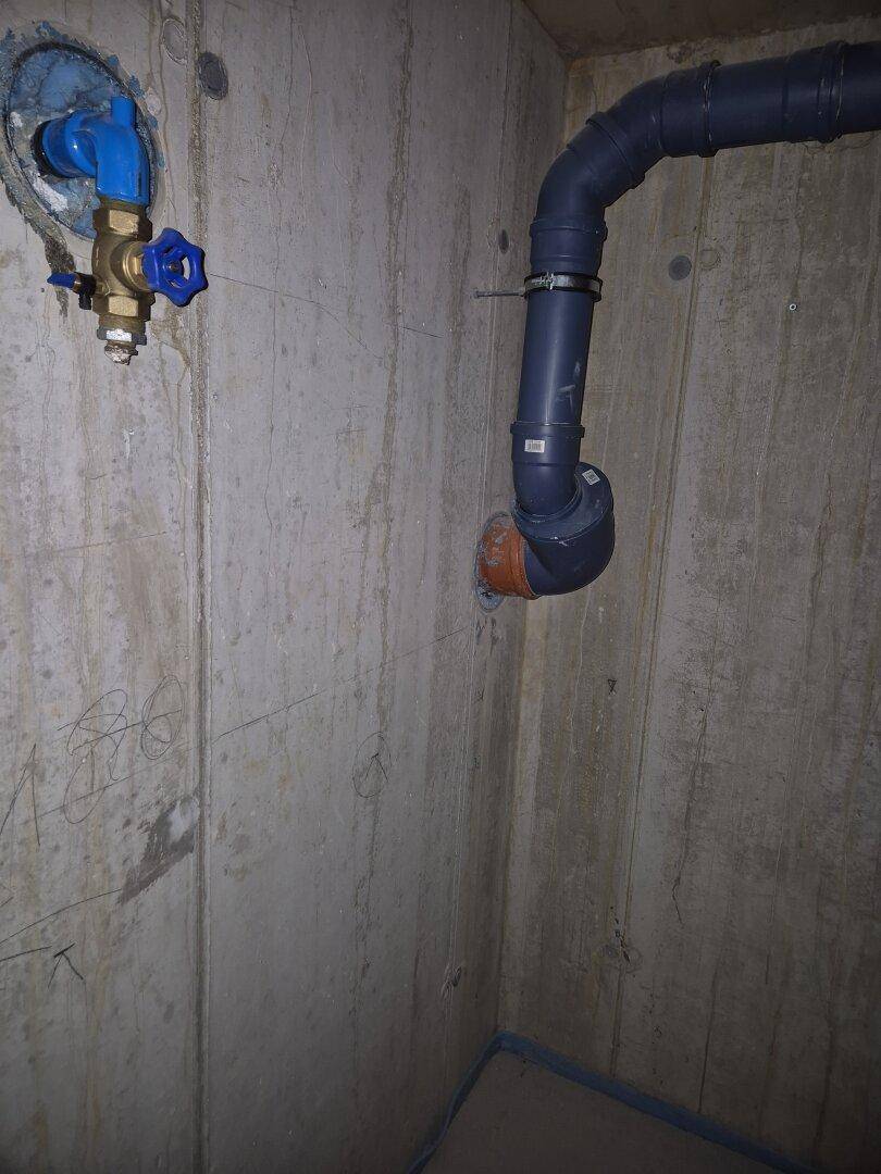 Kellerbereich mit sichtbaren Betonwänden und Wasseranschluss im Rohbauzustand, funktional und robust.