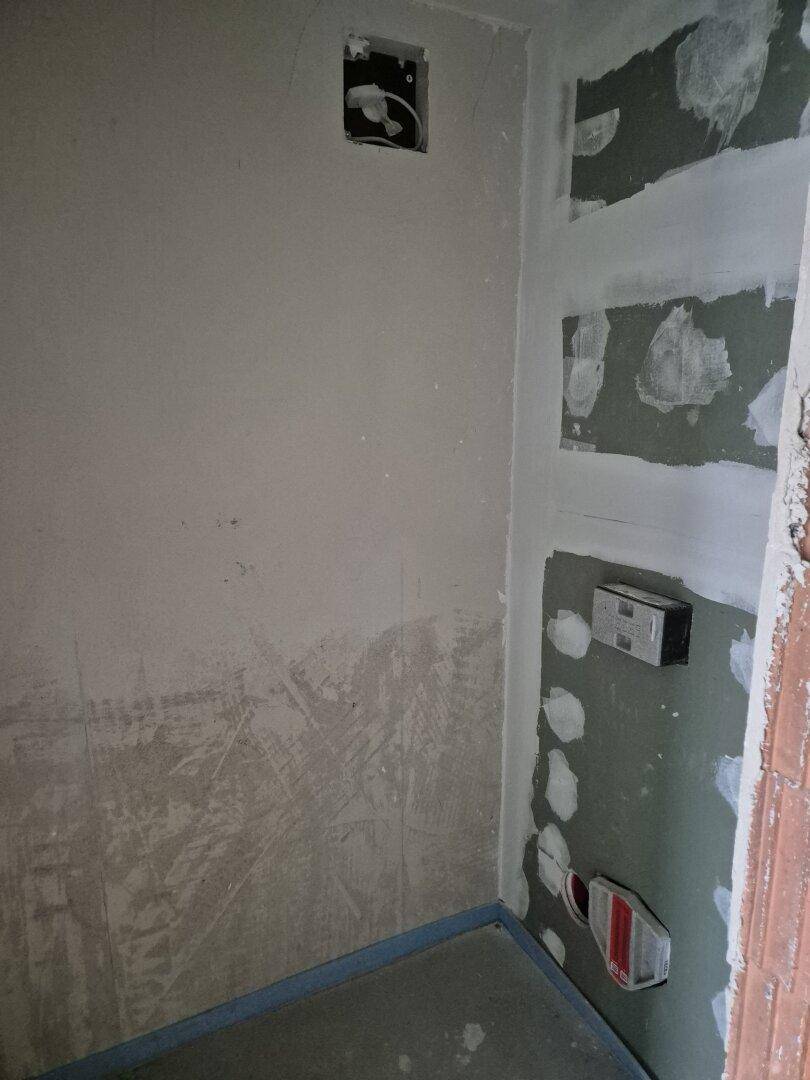 Ecke eines unfertigen Badezimmers mit Vorbereitung für ein Wand-WC im Neubau.