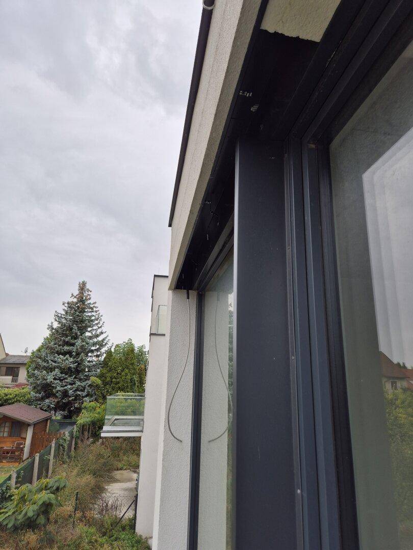 Außenansicht eines Gebäudes mit modernen Fensterrahmen und Blick auf den Gartenbereich.