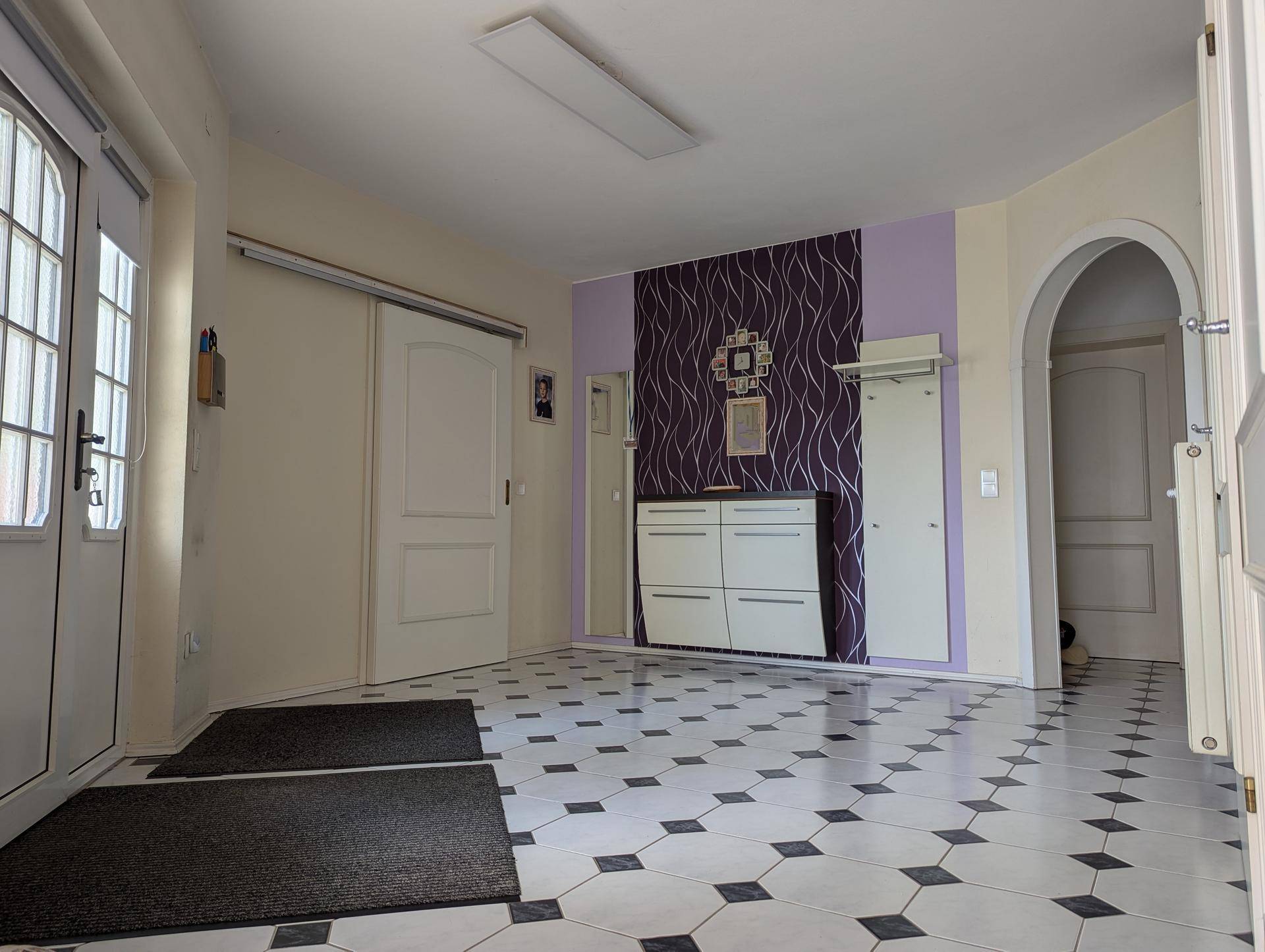 Geräumiger Eingangsbereich mit gemusterten Fliesen, Garderobe und dekorativer Wandgestaltung.