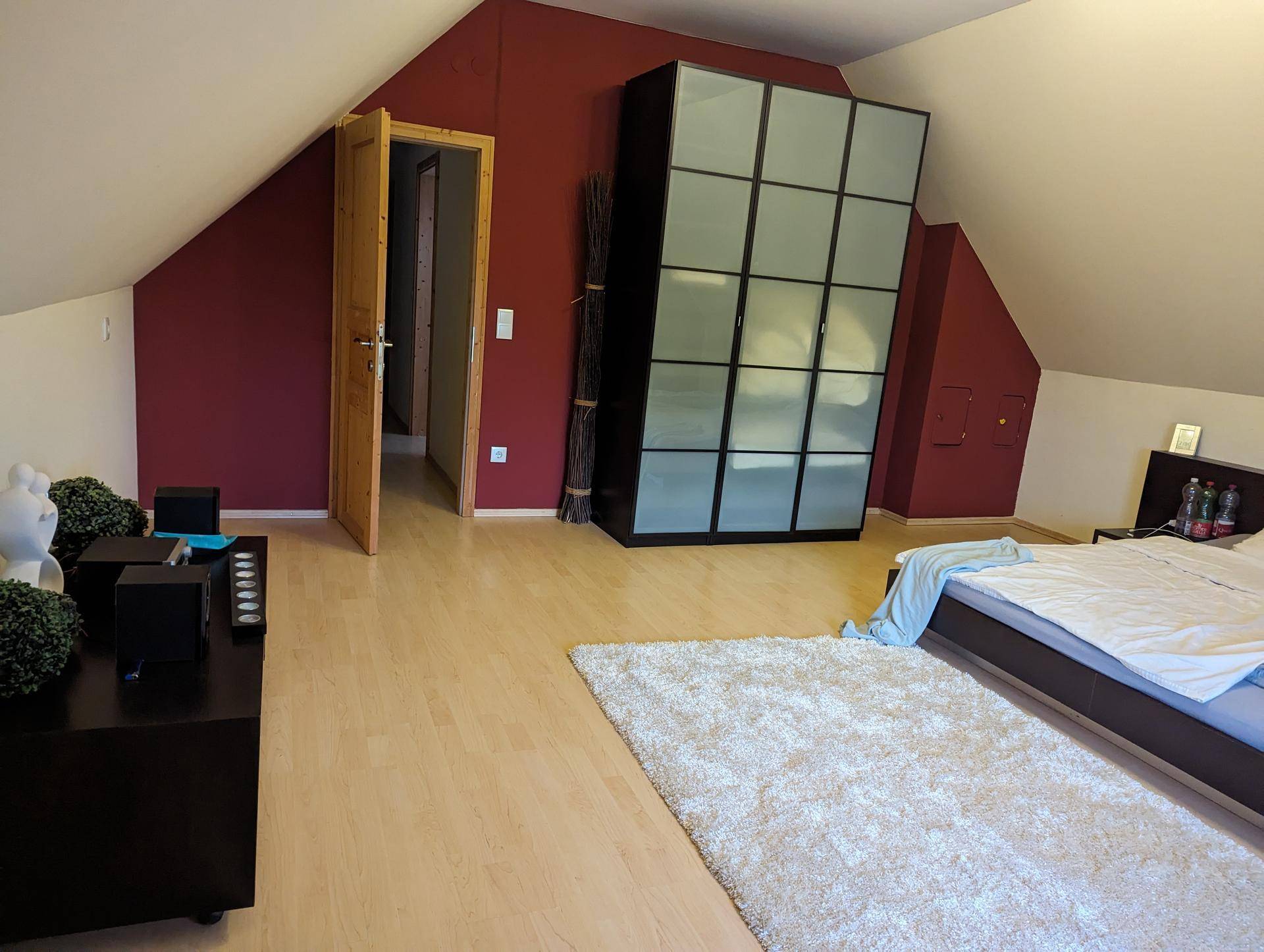 Dachgeschoss-Schlafzimmer mit schrägen Wänden, modernem Kleiderschrank und hellem Boden.