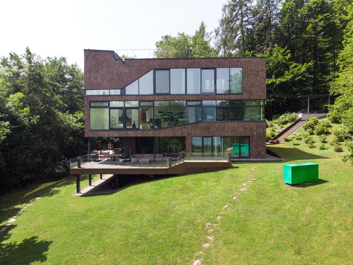 Architektonisch anspruchsvolles Wohnhaus mit großzügigen Glasflächen und weitläufiger Holzterrasse im Grünen.