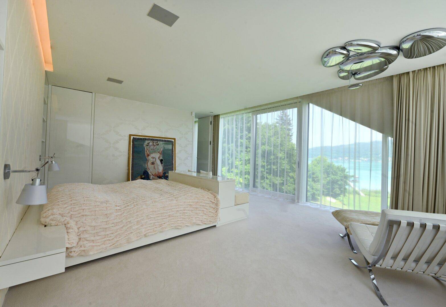 Helles Schlafzimmer mit raumhohen Fenstern, die einen atemberaubenden Blick auf den See bieten.